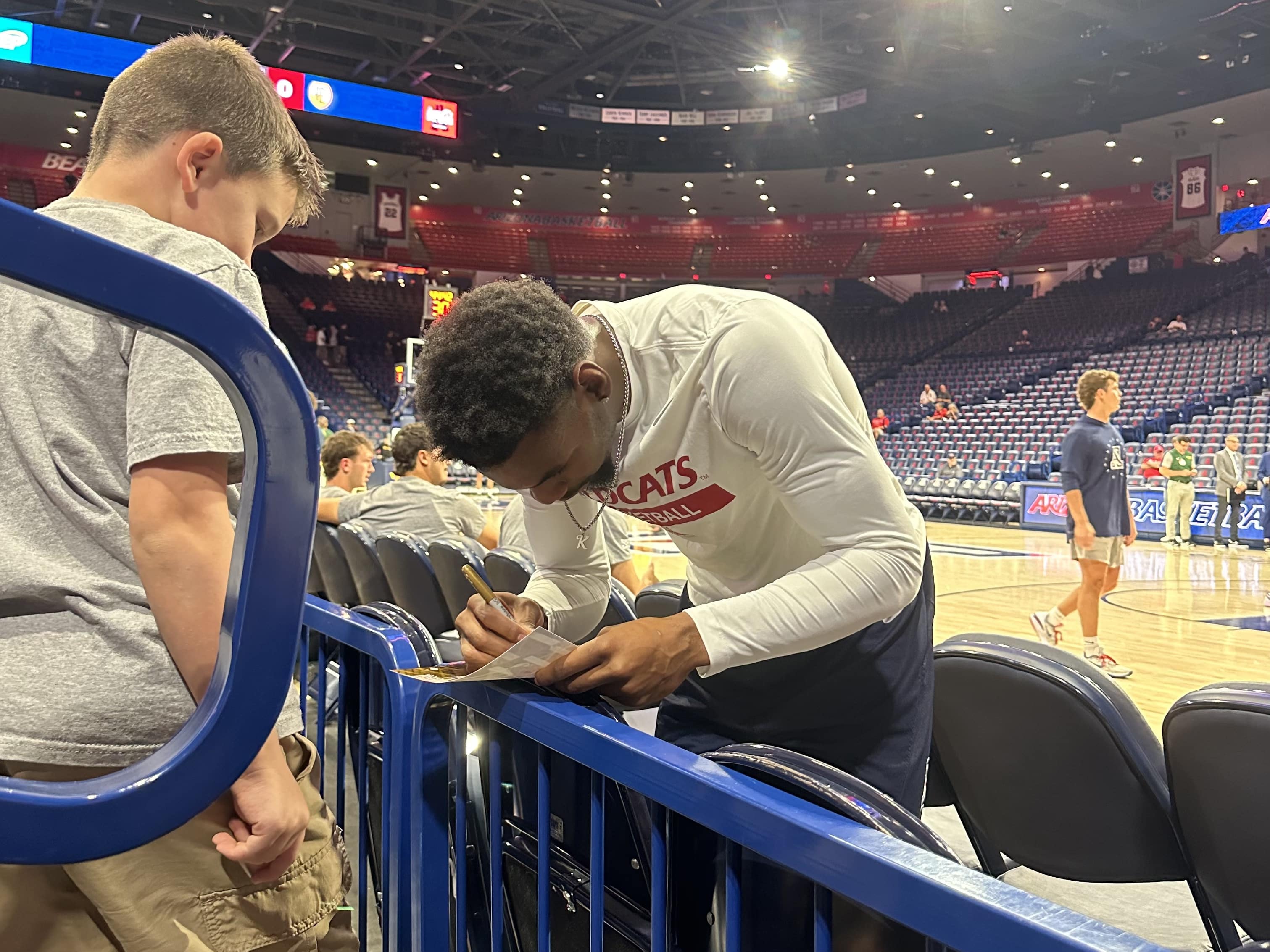 Arizona basketball player KJ Lewis signs autograph for a young fan during warm ups on Monday, Oct. 28.