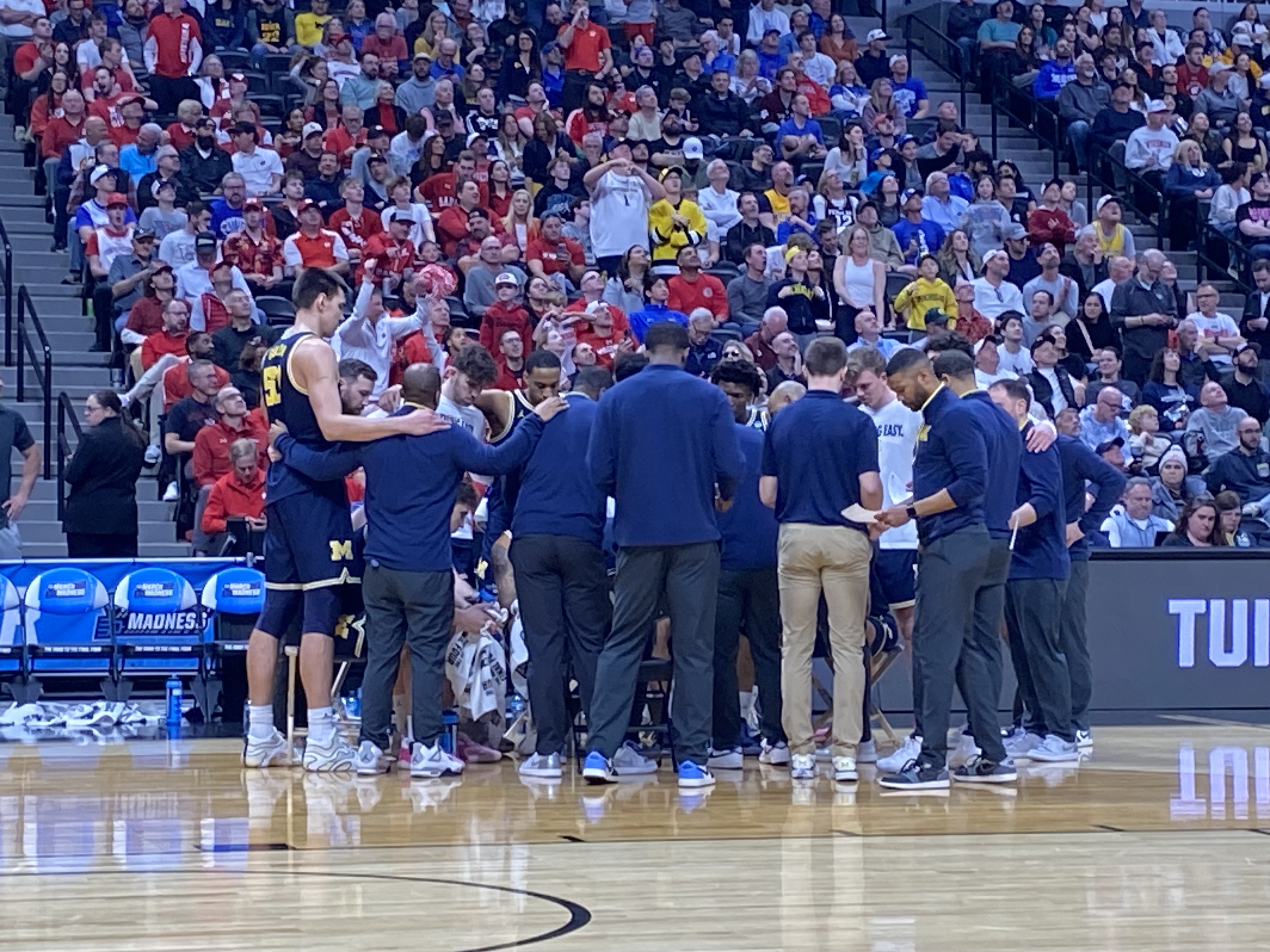 Michigan basketball huddles during a timeout in its win against Texas A&M (Photo Credit: Mihir Sinhasan, CBB Review)